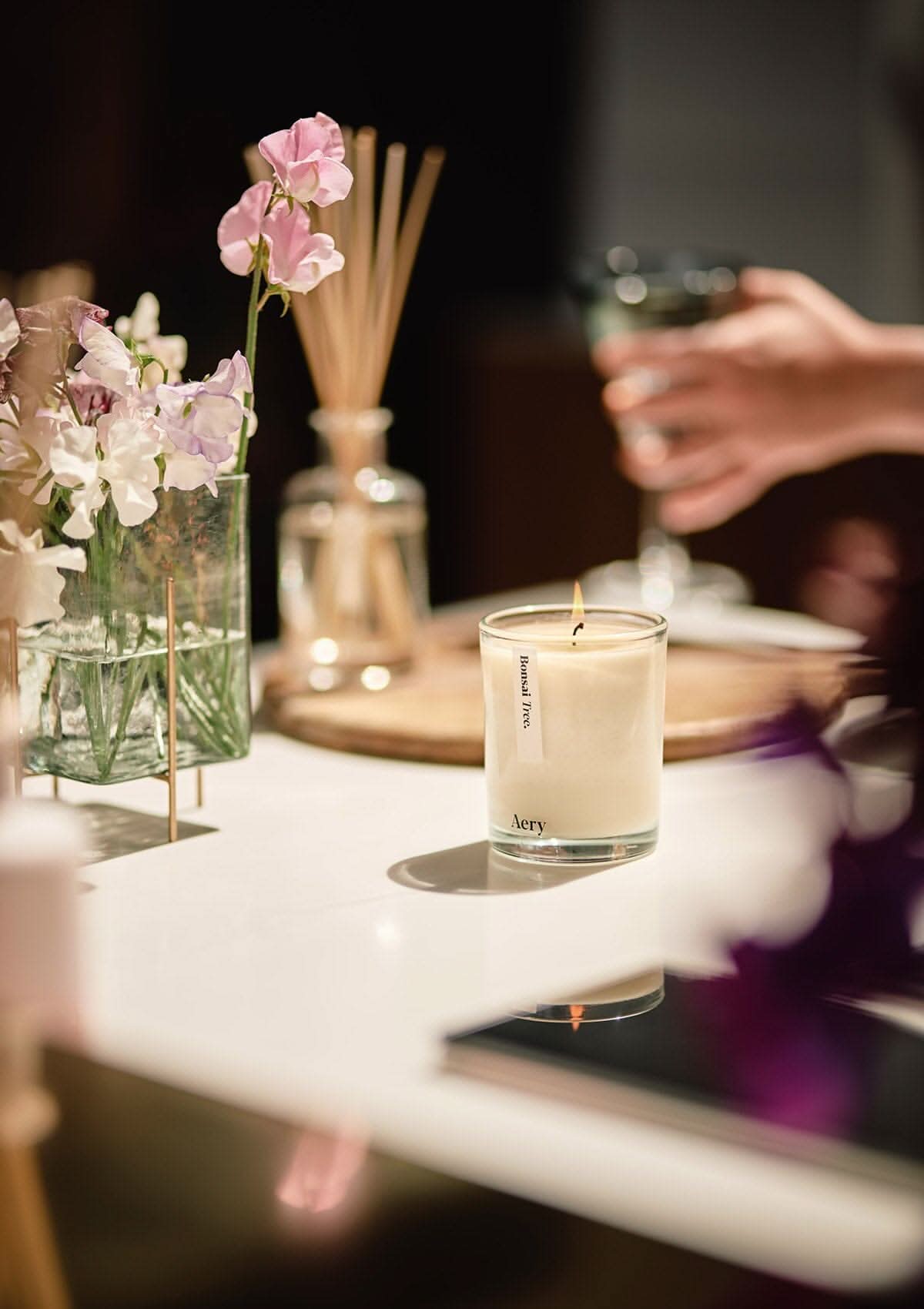 Cream Bonsai Tree candle by Aery displayed next to vase of flowers placed on kitchen worktop